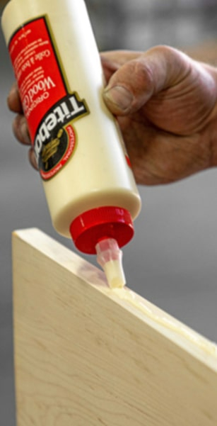 Adhesive in a man's hand gluing a wooden board